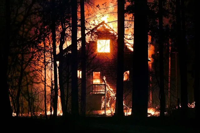 A home burns in Highland Township, Wisconsin, on May 14, 2013. Crews from Wisconsin and Minnesota tried to control a rapidly growing wildfire in northwestern Wisconsin that forced evacuations of the sparsely populated area.  Several structures were destroyed in a mostly rural and wooded area as the forest fire grew to 9 square miles, the Wisconsin Department of Natural Resources said. (Photo by Clint Austin/The Duluth News-Tribune)