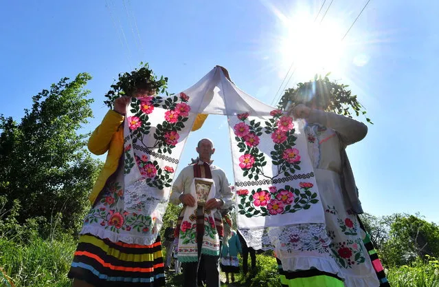 Local women wearing traditional costume h as they perform the Yurievsky Khorovod (Yuriev Round Dance) ancient rite in the village of Pogost. On May 6, Belarus celebrates the day of spring and harvest feast, a tradition that dates back to centuries ago when the Slavs used to let livestock to graze in the fields for the first time after winter. Now, only the Belarusian village of Pogost performs the rite. (Photo by Viktor Drachev/TASS)