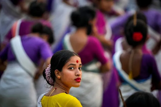 An Assamese girl in traditional attire waits to practice Bihu dance with others ahead of an event in Guwahati, India, Tuesday, April 11, 2023. Around 11,000 Bihu dancers and musicians will perform together for Guinness World Record in the largest folk dance performance category on April 14. (Photo by Anupam Nath/AP Photo)