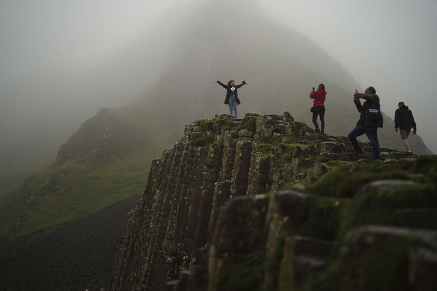 Tourists pose for pictures as they visit the Giant's Causeway, near Bushmills, County Antrim, Northern Ireland, Monday, July 21, 2025. (Photo by Francisco Seco/AP Photo)