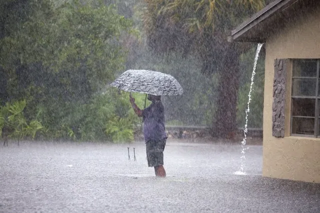 A man stops to take pictures of his flooded neighborhood along Southwest Third Street and Southwest Fourth Avenue in Dania Beach, Florida on April 13, 2023. (Photo by Carline Jean/South Florida Sun-Sentinel vía AP Photo)