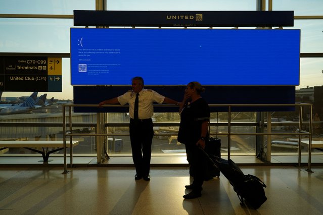 United Airlines employees wait by a departures monitor displaying a blue error screen, also known as the “Blue Screen of Death” inside Terminal C in Newark International Airport, after United Airlines and other airlines grounded flights due to a worldwide tech outage caused by an update to Crowdstrike's “Falcon Sensor” software which crashed Microsoft Windows systems, in Newark, New Jersey, U.S., July 19, 2024. (Photo by Bing Guan/Reuters)