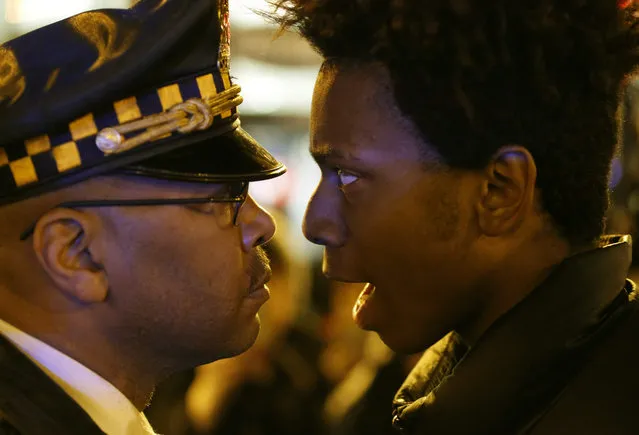 Lamon Reccord, right, stares and yells at a Chicago police officer "Shoot me 16 times" as he and others march through Chicago's Loop Wednesday, November 25, 2015, one day after murder charges were brought against police officer Jason Van Dyke in the killing of 17-year-old Laquan McDonald. (Photo by Charles Rex Arbogast/AP Photo)