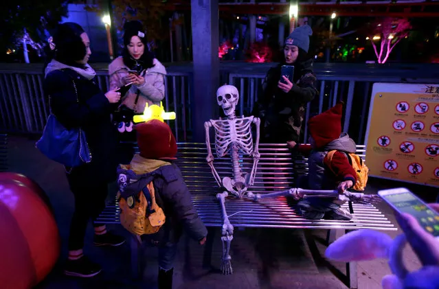People stand around a fake skeleton ahead of a Halloween parade at Happy Valley park in Beijing, China October 31, 2016. (Photo by Jason Lee/Reuters)
