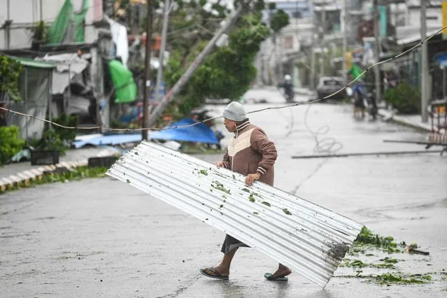 A local resident carries a sheet metal damaged after Cyclone Mocha's crashed ashore, in Kyauktaw in Myanmar's Rakhine state on May 14, 2023. (Photo by Sai Aung Main/AFP Photo)