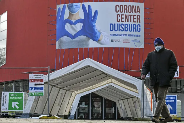 A man with a face mask walks past the Corona Center in Duisburg, Germany, Monday, January 25, 2021. The former Musical theater has been turned into a COVID-19 test and vaccination center. Vaccinations outside care homes and hospitals are delayed. (Photo by Martin Meissner/AP Photo)