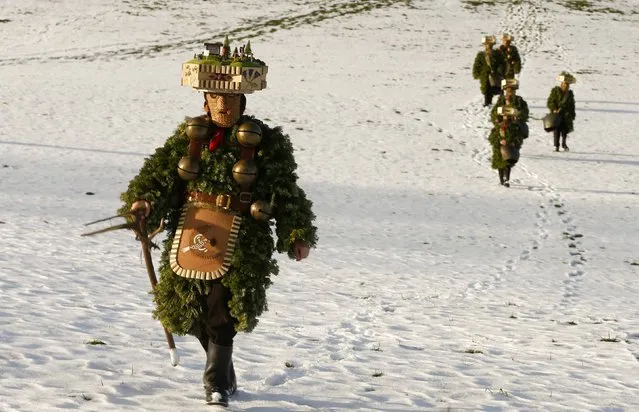 Men dressed as “Chlaeuse”, figures that scare away evil spirits, carry round bells and cowbells as they walk over a partially snow-covered meadow during the traditional “Syvesterchlausen” near the northeastern village of Urnaesch January 13, 2015. Every year on December 31 and January 13, groups of “Chlaeuse” walk through the countryside of the Canton of Appenzell-Ausserrhoden. (Photo by Arnd Wiegmann/Reuters)
