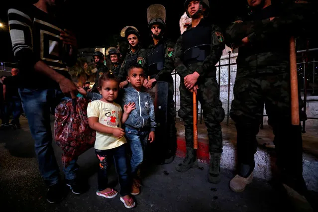 Children walk as members of Palestinian security forces stand guard during a protest calling on President Mahmoud Abbas to end financial sanctions on Palestinians in Gaza, in Ramallah, in the occupied West Bank on June 14, 2018. (Photo by Mohamad Torokman/Reuters)