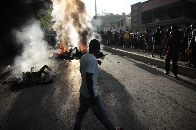 Bystanders gather around the bodies of alleged gang members that were set on fire by a mob after they were stopped by police while traveling in a vehicle in the Canape Vert area of Port-au-Prince, Haiti, Monday, April 24, 2023. (Photo by Joseph Odelyn/AP Photo)