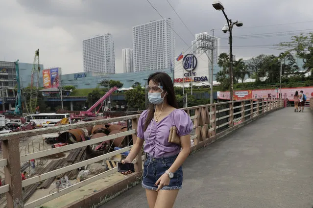 A woman wearing a face mask and shield to prevent the spread of the coronavirus walks outside a mall in Quezon City, Philippines on Monday, February 15, 2021. The Philippine government's approval for reopening many movie theaters, video game arcades and other leisure businesses closed since last year was postponed at least another two weeks after mayors feared it will bring new coronavirus infections. (Photo by Aaron Favila/AP Photo)