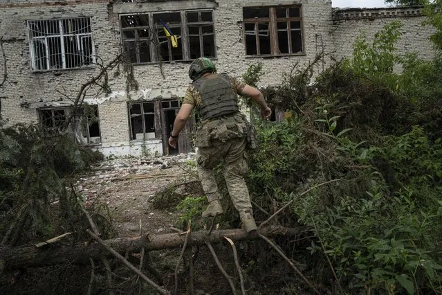 A Ukrainian serviceman of the 68th Oleksa Dovbush hunting brigade runs to his position in the recently retaken village of Blahodatne, Ukraine, Saturday, June 17, 2023. (Photo by Evgeniy Maloletka/AP Photo)