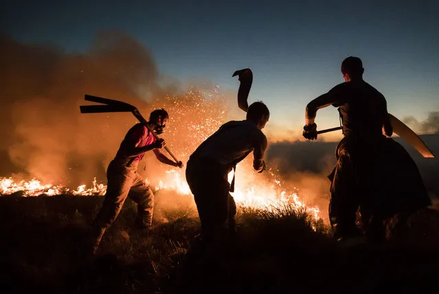 In this photo taken on Thursday, June 28, 2018, firefighters tackle a wildfire on Winter Hill near Bolton, England. Dozens of people have been evacuated from homes in northwest England as firefighters continue to tackle a blaze spreading across tinder-dry moorland. (Photo by Danny Lawson/PA Wire via AP Photo)