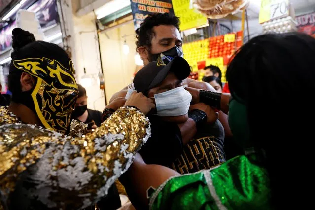 Lucha libre wrestlers Bandido and Espectrito, encourage mask-less people to wear masks, as a measure of prevention against the coronavirus at the Central Abastos market, in Mexico City, Mexico on March 10, 2021. Mexico's famous lucha libre wrestlers turned Latin America's largest wholesale food market into a battleground against COVID-19 this week, barging down walkways to urge people to wear masks to contain the virus. (Photo by Carlos Jasso/Reuters)