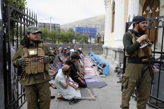 Afghan people offer Eid al-Fitr prayers as Taliban fighters stand guard at a mosque in Kabul, Afghanistan, Wednesday, June 28, 2023. Muslims celebrate the holiday to mark the willingness of the Prophet Ibrahim (Abraham to Christians and Jews) to sacrifice his son. During the holiday, they slaughter sheep or cattle, distribute part of the meat to the poor and eat the rest. (Photo by Siddiqullah Khan/AP Photo)