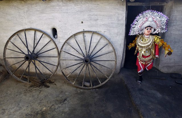 Traditional dancer Fotik Mahato, 7, walks out of his house to take part in the day long village festival of Chhau, at Malti village in Purulia district, in the eastern Indian state of West Bengal January 31, 2015. Chhau is a traditional folk dance which involves singing, dancing and drama, and is performed to celebrate the successful harvest during springtime, according to the villagers. (Photo by Rupak De Chowdhuri/Reuters)