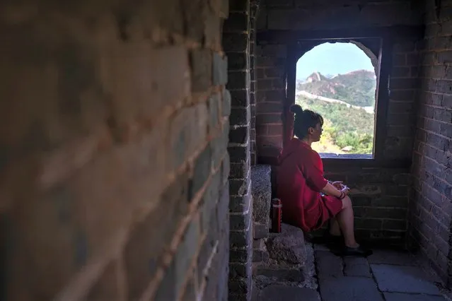A woman sits in the shade on a hot day in a tower along the Jinshaling section of the Great Wall of China, north of Beijing in northern China's Hebei Province, Wednesday, July 5, 2023. (Photo by Mark Schiefelbein/AP Photo)