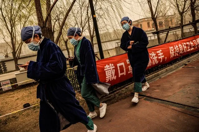 Nurses go about their day during morning rush hour as Beijing, China, is hit by a sandstorm, March 15, 2021. (Photo by Thomas Peter/Reuters)