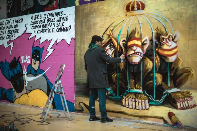 A street artist paints graffiti in Barcelona on February 21, 2021 criticizing Spain's monarchy in support of imprisoned rap artist Pablo Hasel, convicted to jail for glorifying terrorism and insulting Spain's former king in lyrics, after five nights of riots. (Photo by Matthias Oesterle/ZUMA Wire/Rex Features/Shutterstock)