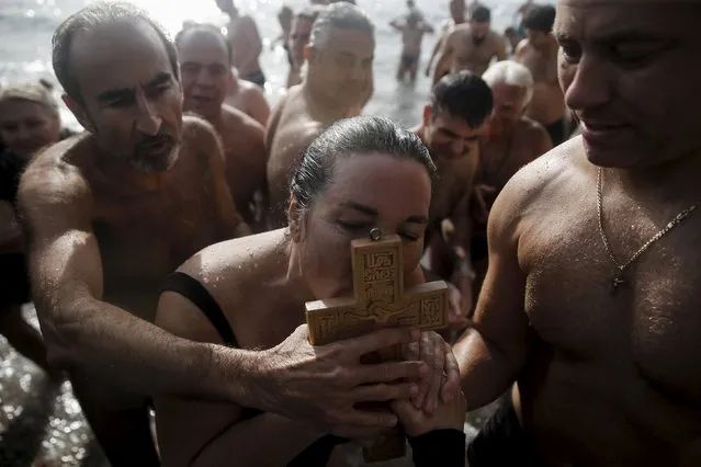 An Orthodox faithful kisses a wooden crucifix retrieved from the water by Russian Andreas Pyetakov (R) during Epiphany day celebrations in the southern suburb of Faliro in Athens, Greece, January 6, 2016. (Photo by Alkis Konstantinidis/Reuters)