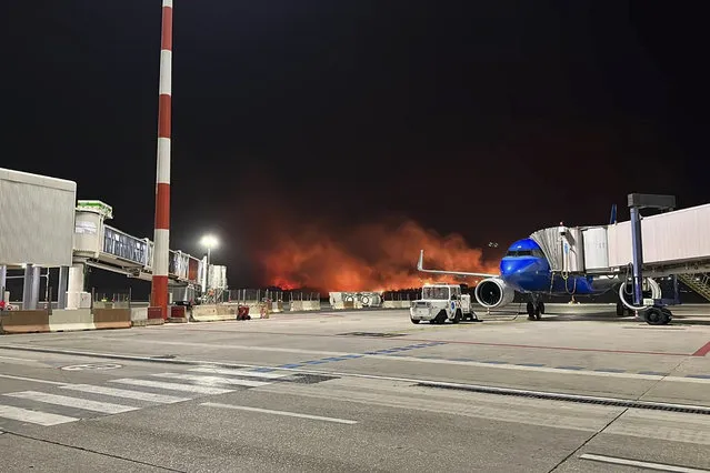 This photo provided by Palermo Airport Press Office shows plumes of fire and smoke covering the hills surrounding Palermo's airport, Sicily, Italy, late Monday night, July 24, 2023, causing its shutdown and leaving planes trapped on the tarmac. The airport reopened at 11am (9gmt) Tuesday 25 only for departing planes, after twentyfour flights were cancelled overnight and four were sent to the nearby airport in Trapani. (Photo by Palermo Airport Press Office via AP Photo)