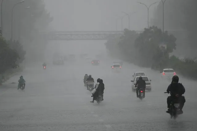 Commuters make their way along a motorway during a heavy rainfall in Islamabad on August 17, 2023. (Photo by Farooq Naeem/AFP Photo)
