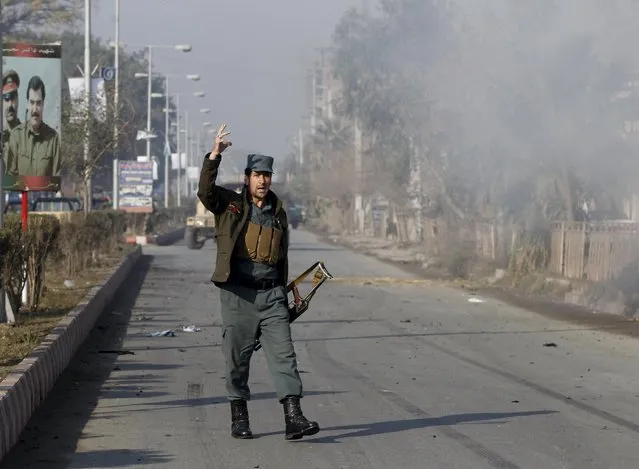 An Afghan policeman reacts as smoke billows during an attack near the Pakistani consulate in Jalalabad, Afghanistan January 13, 2016. (Photo by Reuters/Parwiz)