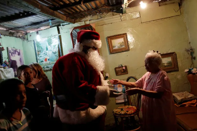 Santa Claus greets a woman during a visit to residents of the slum of Petare in Caracas, Venezuela, December 11, 2016. (Photo by Ueslei Marcelino/Reuters)