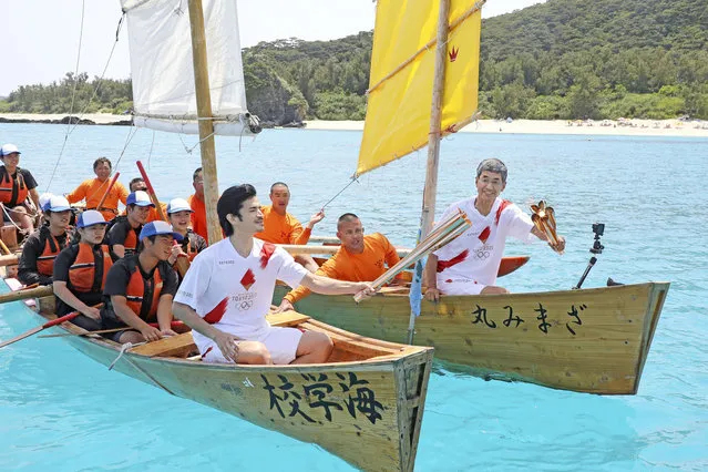 The Olympic flame is passed from torch to torch on traditional rowboats during the Tokyo 2020 Olympics torch relay off Zamami in Japan's southernmost island prefecture of Okinawa, southwestern Japan, May 2, 2021, in this photo relased by Kyodo. (Photo by Kyodo News via Reuters)