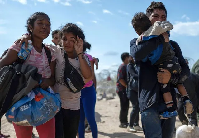 A migrant family from Venezuela reacts after breaking through a razor wire barricade into the United States after waiting for hours on a river bank on the Rio Grande river in Eagle Pass, Texas on September 25, 2023. Dozens of migrants arrived at the US-Mexico border on September 22, 2023, hoping to be allowed into the United States, with US border forces reporting 1.8 million encounters with migrants in the last 12 months. (Photo by Andrew Caballero-Reynolds/AFP Photo)