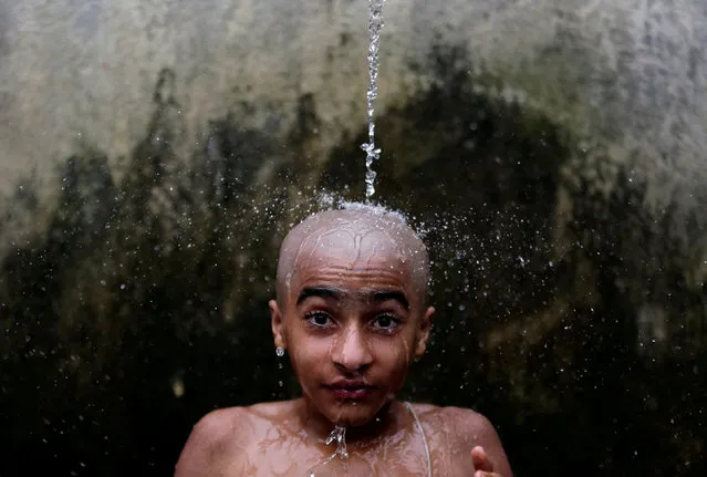 A young Hindu priest takes a holy bath as part of a ritual during the Janai Purnima, or Sacred Thread, festival at the Pashupatinath temple in Kathmandu, Nepal August 26, 2018. Hindus take holy baths and change their sacred threads, also known as janai, for protection and purification during the festival. (Photo by Navesh Chitrakar/Reuters)