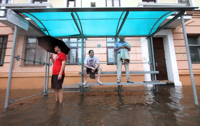 People wait for the bus in a flooded bus stop during heavy rain in Minsk, Belarus on August 12, 2014. (Photo by Sergei Gapon/AFP Photo)