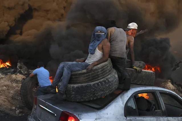Palestinians burn tires during a night demonstration against the expansion of a Jewish settlement on the lands of Beita village, near the occupied West Bank city of Nablus, on June 23, 2021. (Photo by Abbas Momani/AFP Photo)