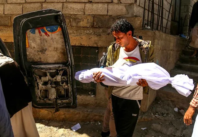 A Yemeni man carries the body of a child killed in a mortar shell attack on the country's flashpoint southern city of Taez, as clashes between fighters from the Popular Resistance Committees, loyal to Yemen's fugitive President and Shiite Huthi rebels continue on February 3, 2016. The city of Taez is held by loyalists of Yemen's internationally recognised government, but it has been besieged by the Iran-backed rebels for months. (Photo by Ahmad Al-Basha/AFP Photo)