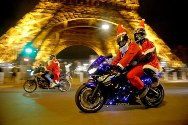 People dressed in Santa Claus costumes ride on motorbikes near the Eiffel Tower during “Carabalade”,  the annual Santa Claus parade in Paris, France, December 20, 2018. (Photo by Charles Platiau/Reuters)