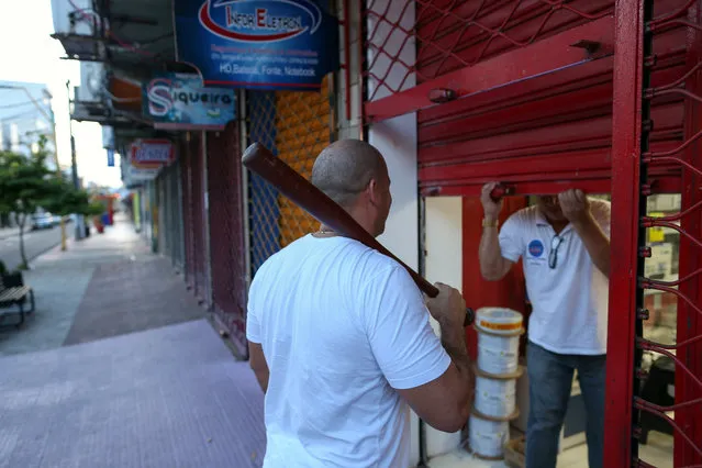 A private security officer (L) escorts a man who is closing his store due to high levels of violence in the city of Manaus, following a prison escape incident, Brazil, January 6, 2017. (Photo by Michael Dantas/Reuters)