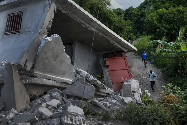 Residents walk past a collapsed building in Saint-Louis-du-Sud, Haiti, Monday, August 16, 2021. A 7.2-magnitude earthquake struck the southwestern part of the hemisphere's poorest nation on Aug. 14. (Photo by Matias Delacroix/AP Photo)