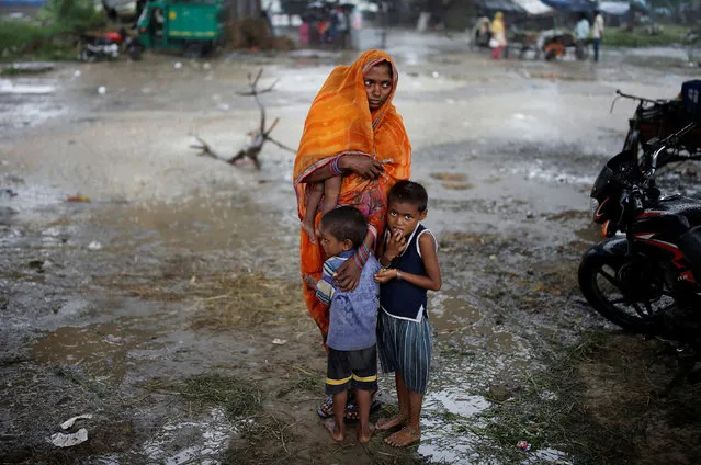 A woman stands with her children as she waits to receive a dose of COVAXIN coronavirus disease (COVID-19) vaccine manufactured by Bharat Biotech, during a vaccination drive organised by SEEDS, an NGO which normally specialise in providing relief after floods and other natural disasters, at an under-construction flyover in New Delhi, India, August 31, 2021. (Photo by Adnan Abidi/Reuters)