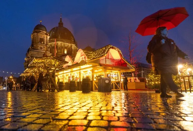A person strolls past Christmas lights and decorations at the outdoor Christmas market at Humboldt Forum in front of Berlin Cathedral (Berliner Dom) in central Berlin, Germany on December 11, 2023. (Photo by Lisi Niesner/Reuters)