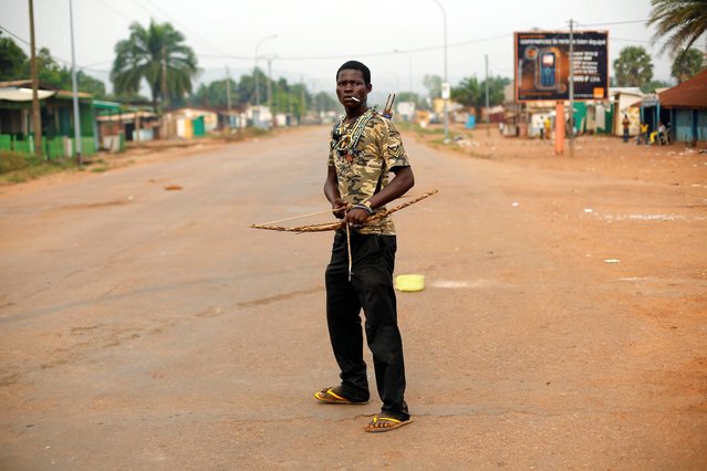 An anti-Balaka Christian militiaman holding a bow and arrow stands in, what days before, was a predominantly Muslim area of the Miskin district of Bangui, Central African Republic, Tuesday February 4, 2014. All Muslim shops on the avenue leading to PK5 have been looted in the past 2 days, as anti-Balaka militiamen push back Muslim factions, opening the gates for mass looting by Christian residents. (Photo by Jerome Delay/AP Photo)