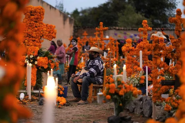 Relatives prepare to spend the night next to the tomb of their loved ones during Day of the Dead festivities at the the Arocutin cemetery in Michoacan state, Mexico, Monday, November 1, 2021. (Photo by Eduardo Verdugo/AP Photo)