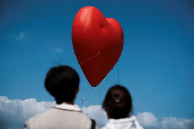 Visitors look at a giant inflatable heart called “Chubby Hearts”, an installation by designer Anya Hindmarch, on Valentine's Day in Hong Kong on February 14, 2024. (Photo by Lam Yik/Reuters)