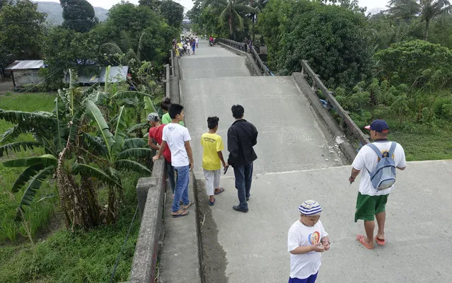 Residents look at the collapsed portion of a bridge in Surigao hours after a powerful earthquake rocked Surigao del Norte province Saturday, February11, 2017 in southern Philippines. The late Friday quake with a magnitude of 6.5 roused residents from sleep in the province, sending hundreds to flee their homes. (Photo by AP Photo)