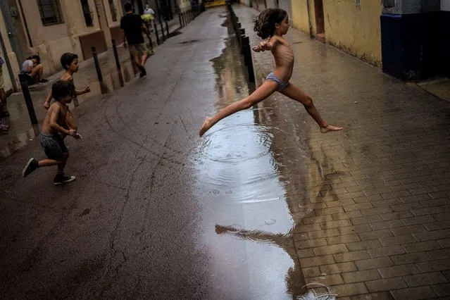 Children jump over a puddle of water as they play during a rainstorm on a street in Barcelona, Spain, Saturday, September 18, 2021. (Photo by Emilio Morenatti/AP Photo)