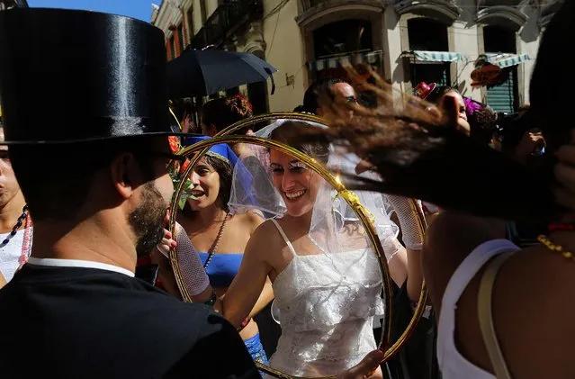 A reveler dressed as a bride holds giant wedding rings at the Boitata block party, a pre-Carnival celebration in Rio de Janeiro, February 23, 2014. (Photo by Leo Correa/Associated Press)