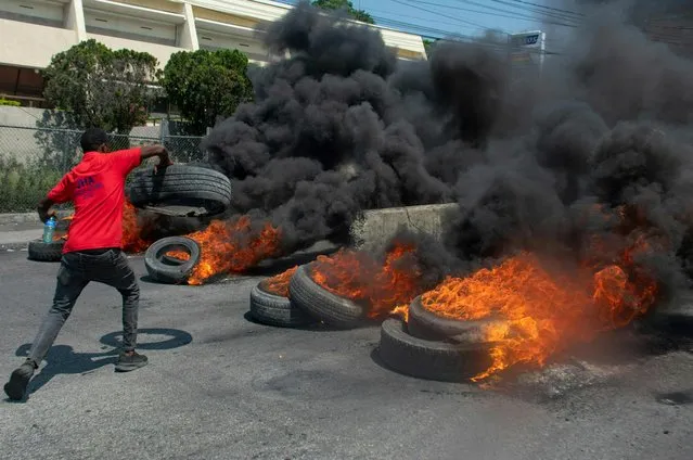 A protester burns tires during a demonstration following the resignation of its Prime Minister Ariel Henry, in Port-au-Prince, Haiti, on March 12, 2024. A political transition deal in Haiti marks a key step forward for the violence-ravaged country but far more needs to be done, with some experts warning the situation could deteriorate further. (Photo by Clarens Siffroy/AFP Photo)