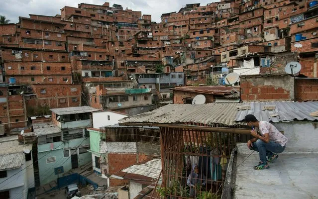 Sister Tranquilina Garcia talks to a neighbor from inside a parish house in Caracas, Venezuela, Thursday, May 2, 2019. Popular Venezuelan opposition leader Leopoldo López says he expects the country's military will step up to overthrow President Nicolas Maduro despite setbacks. (Photo by Rodrigo Abd/AP Photo)