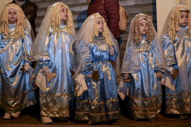 Children dressed as angels attend a procession for the Our Lady of Sorrows, in Verbicaro in the southern tip of Italy, early Friday, March 29, 2024. Devotes who have made the vow to the Our Lady of Sorrows pour on Good Friday through the streets and alleys of Verbicaro at night where they spread their blood on the portals and steps of places of worship after having flagellated their legs with shards of glass in remembrance of the flagellation of Jesus Christ. (Photo by Valeria Ferraro/AP Photo)