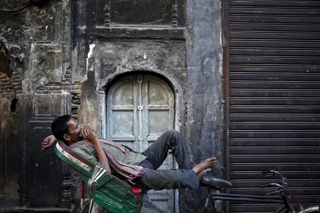 A rickshaw puller takes rest in front of the closed door of a house in the old quarters of Delhi, India, May 13, 2015. (Photo by Anindito Mukherjee/Reuters)