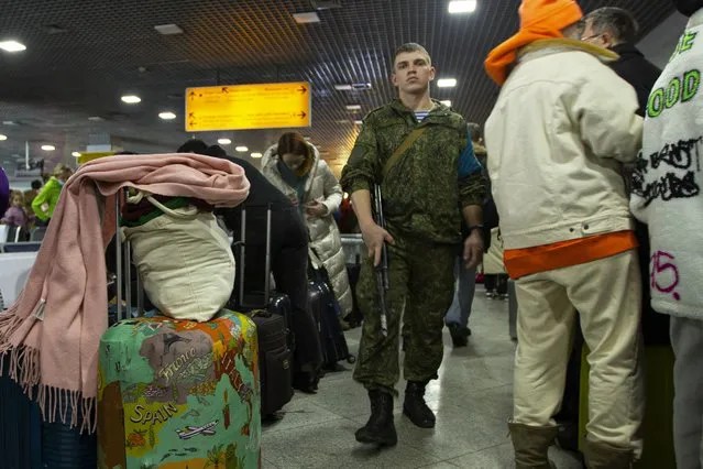 A Russian peacekeeper, center, patrols a hall where Russian citizens wait to board aircrafts of the Russian Aerospace Forces to leave Kazakhstan for Moscow at an airport in Almaty, Kazakhstan, Sunday, January 9, 2022. The first three aircraft of the Aerospace Forces with the Russians flew from Kazakhstan to Moscow. Three aircraft of the Russian Aerospace Forces flew from Kazakhstan to Moscow together with the Russians who wished to evacuate. TASS was informed about this by a representative of the Russian peacekeepers. (Photo by Vasily Krestyaninov/AP Photo)