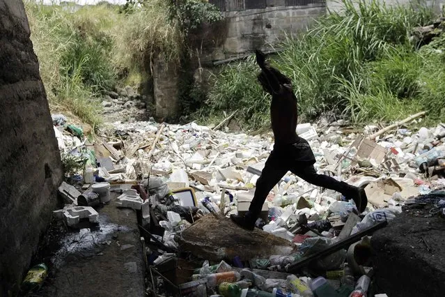 A local jumps over the La Cangreja River filled with rubbish and plastic bottles, in northeastern San Jose, Costa Rica, 21 April 2016. Although Costa Rica maintains 25% of its protected territory, the country is losing its biological resources, mainly due to climate change, pollution and lack of awareness of the population on the handling of recyclable waste. Earth Day is celebrated on 22 April. (Photo by Jeffrey Arguedas/EPA)